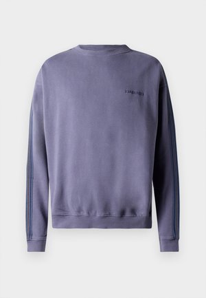 Sweatshirt roxo com mangas longas, punhos e barra canelados, apresentando riscas laterais num tom de azul mais escuro e um pequeno logótipo na parte de trás.