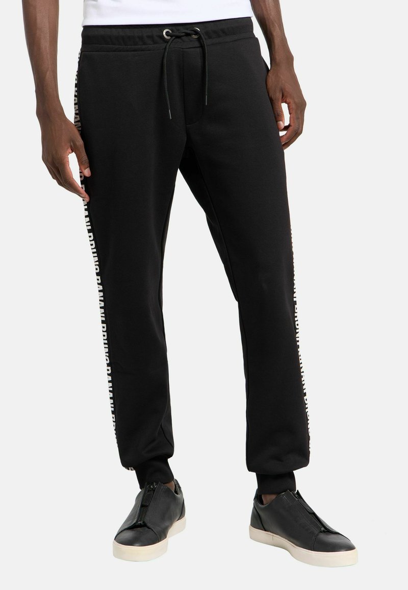 Schwarze Jogginghose mit elastischem Bund und Kordelzug, mit weißem Branding an der Seite. Baumwollmischgewebe mit glatter Textur.