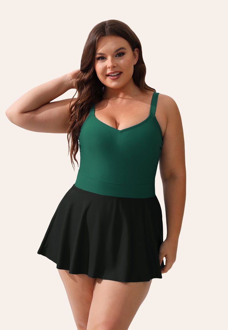 Groene one-piece zwemsuit met een V-hals en dunne bandjes, voorzien van een uitlopende zwarte rok. Glad materiaal met een aansluitend lijfje.