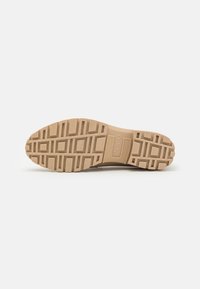 Semelle de chaussure en caoutchouc beige avec des motifs géométriques texturés pour l'adhérence. Marque "ecco" embossée au centre sur le côté.