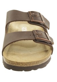 Sandalo in pelle marrone con due fibbie regolabili, soletta in sughero e suola in gomma texture. Presenta un interno neutro di colore beige chiaro.