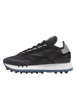 Zwarte lage sneaker met gestructureerd bovenwerk, witte tussenzool, blauwe buitenzool met spikes en grijze hieltab, weergegeven in zijaanzicht.