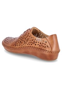 Zapato de cuero marrón claro con patrones recortados, puntera redonda, costura decorativa a lo largo de la suela y una pequeña etiqueta de la marca en el lateral.