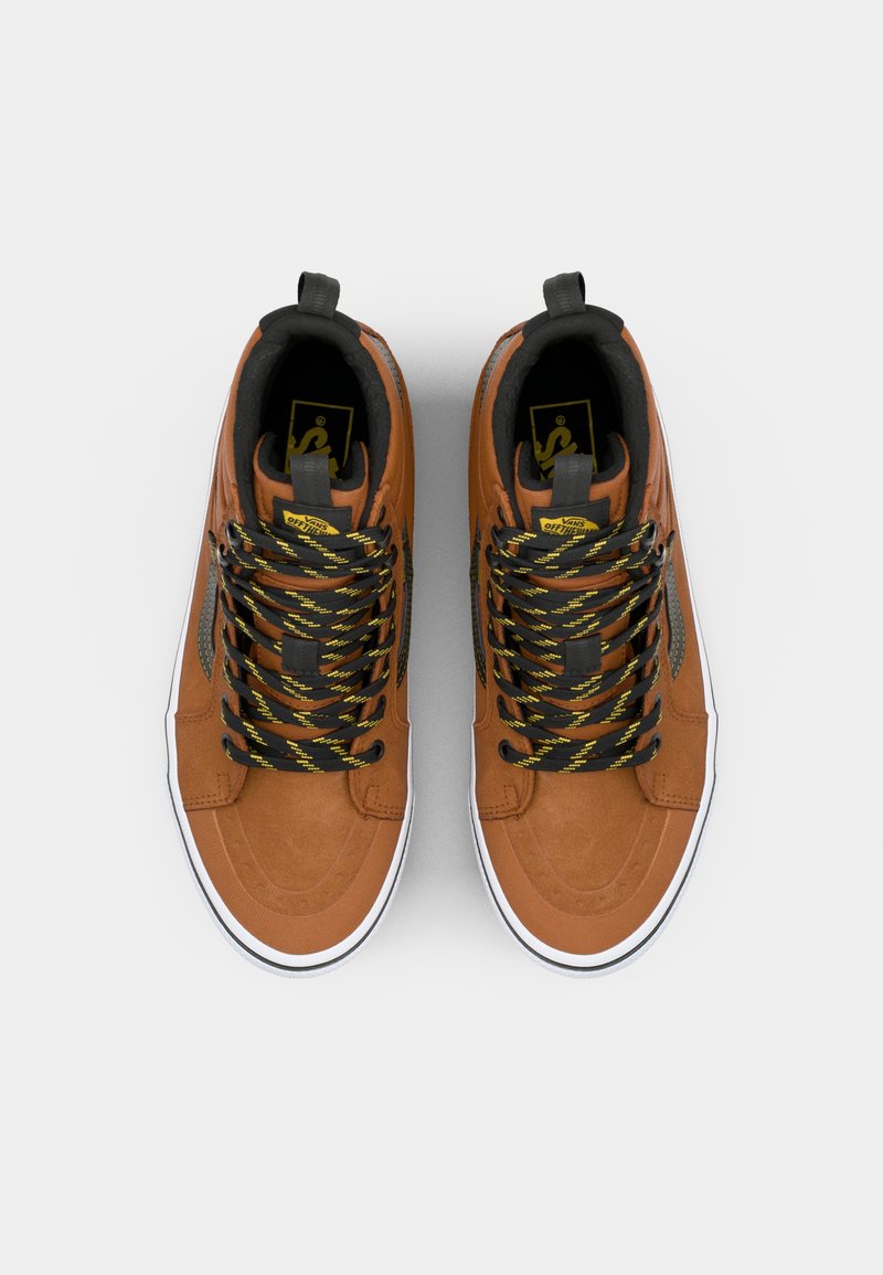 Zapatillas altas de ante marrón con cordones negros y amarillos, suelas de goma blanca y un cuello acolchado negro. Presentan un logo en la lengüeta.