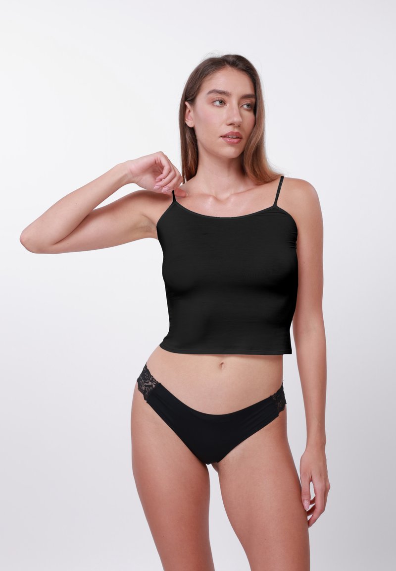 Μαύρο κοντό τοπάκι με λεπτές τιράντες, συνδυασμένο με μαύρο μαγιό σλιπ που έχει δαντελένιες λεπτομέρειες στα πλαϊνά. Ομαλό, εφαρμοστό ύφασμα.