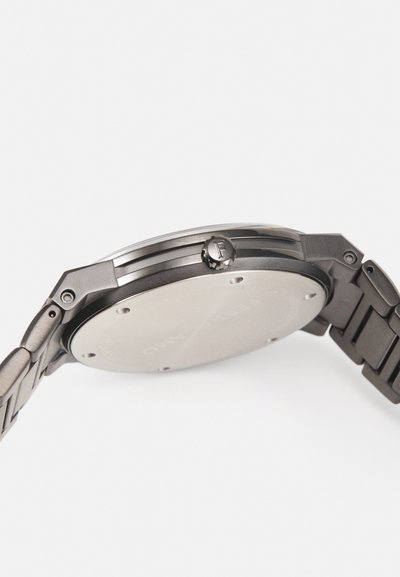 Metal watch with a sleek black finish, featuring a round case and a textured crown. The band is composed of linked metal segments.