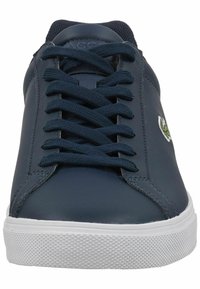 Navy blue leather sneaker with white rubber sole, flat laces, and embroidered green logo on the side. Smooth texture and minimalist design.