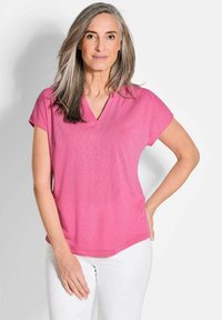 Roze top met korte mouwen en een V-hals ontwerp, gemaakt van zachte stof, met een ontspannen pasvorm en subtiele stikseldetails aan de zoom.