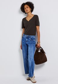 Tmavě šedé tričko s výstřihem do V, světle modré široké džíny, béžové tenisky a hnědá semišová taška se zúženými popruhy.