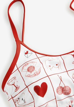 Czerwona i biała koszulka na ramiączkach z wzorem w kratkę, z rysunkowymi motywami, takimi jak serca, wiśnie i wzory florystyczne. Czerwony nadruk wokół dekoltu.