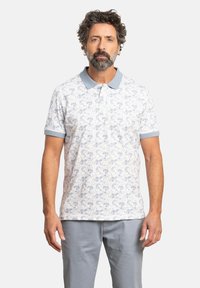 Polo de manga corta en azul claro y blanco, con un patrón floral. Diseño con cuello y puños y cuello en azul claro contrastante.