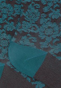 Tessuto scuro con motivo floreale in teal, dalla superficie liscia e con contrasti di tonalità teal solide. Il design a maglia audace mette in risalto dettagli intricati.