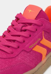Αθλητικό παπούτσι με ροζ σουέτ επάνω μέρος, υφασμάτινες λεπτομέρειες, πορτοκαλί λογότυπο και κορδόνια. Περιλαμβάνει μαλακή πορτοκαλί περιφέρεια και καφέ λάστιχο σόλα.