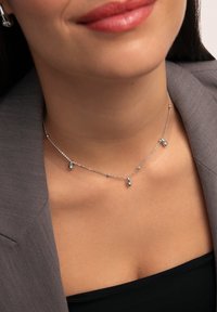 Collier en argent avec une chaîne délicate et cinq pendentifs en forme de goutte d'eau, présentant une finition polie et des accents scintillants subtils.