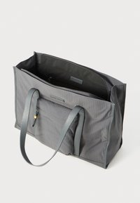 Sac fourre-tout rectangulaire gris avec de longues sangles, poche zippée à l'avant et compartiment principal ouvert avec une poche zippée intérieure visible.