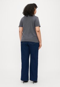 Grå kortermet t-skjorte kombinert med blå vide jeans. Antrekket har en avslappet passform og myk tekstur. Svarte hæler fullfører looken.