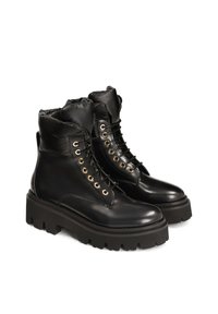 Botas de tobillo de piel negra con un collarín acolchado, parte delantera con cordones, ojales dorados y suelas gruesas de goma negra con un patrón de agarre.
