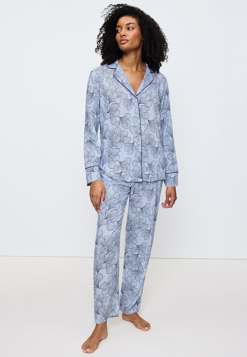 Ljusblå pyjamasset med blommönster, som har långärmad tröja, knapp-up topp och lös passform på byxorna, tillverkad av mjukt tyg.