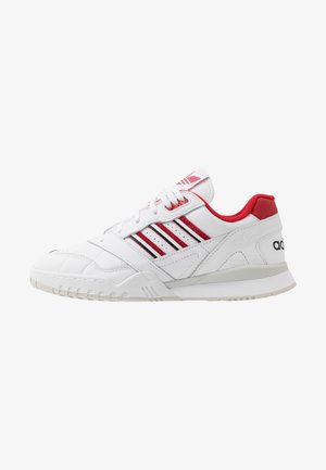 White sneaker with red accents and three striped design. Features leather upper, padded collar, and textured sole for traction.