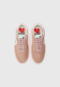Rožinės zomšos sportbačiai su baltais akcentais, turintys tekstūruotą paviršių, rožines raišteles ir spausdintą pado vidų su užrašu „LOVE MOSCHINO“ ir širdies logotipu.