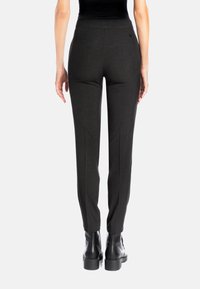 Black tailored trousers with a smooth fabric, slim fit, and subtle texture. Features a mid-rise waist and functional rear pockets.