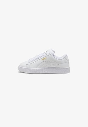 White leather sneakers with a textured rubber sole, flat laces, and gold Puma branding on the side. Rounded toe silhouette.
