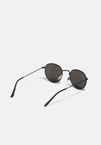 Schwarze Metall-Sonnenbrille mit runden Gläsern und dünnen Rahmen. Verstellbare Nasenpads und elegante, geschwungene Bügel.