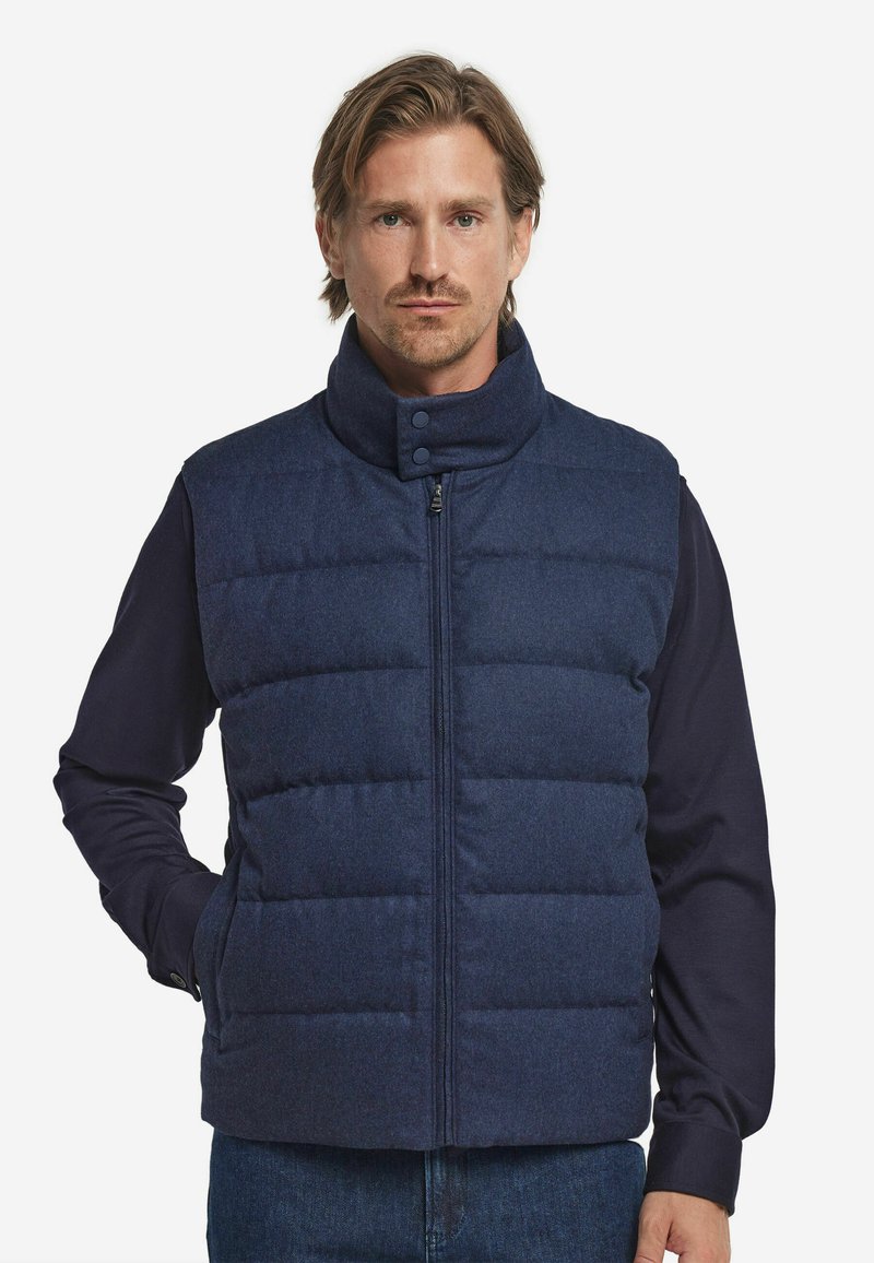 Marineblaue Steppweste mit hohem Kragen, Frontreißverschluss und Druckknöpfen. Verfügt über ein gesteppte Muster und einen weichen, strukturierten Stoff.