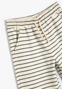 Gestreifte Sweatpants in Creme und Marineblau, ausgestattet mit einem elastischen Bund, Kordelzug und Seitentaschen aus weichem, strukturiertem Stoff.