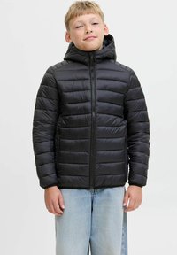 Svart puffjacka med huva, med horisontella quiltade sektioner och en frontdragkedja. Bärs med ljusblå denimjeans.