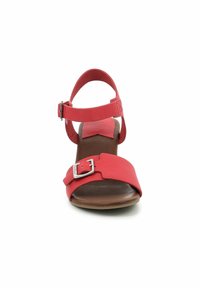 Sandalia de cuero rojo con una tira frontal ancha, correa ajustable en el tobillo, hebilla plateada y una suela acolchada marrón. Diseño de tacón plano.
