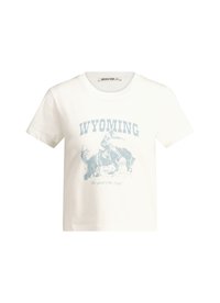 Valkoinen puuvillapaita, jossa on sininen graafinen printti cowboysta hevosen selässä ja teksti "WYOMING" alla tekstillä "Lännen henki". Lyhyet hihat.