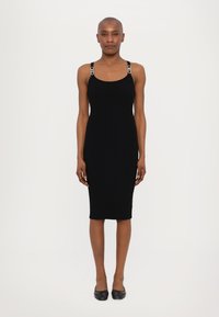 Rochie bodycon neagră cu nervuri, cu bretele late, prezentând accente metalice. Design până la genunchi, siluetă ajustată și textură netedă.
