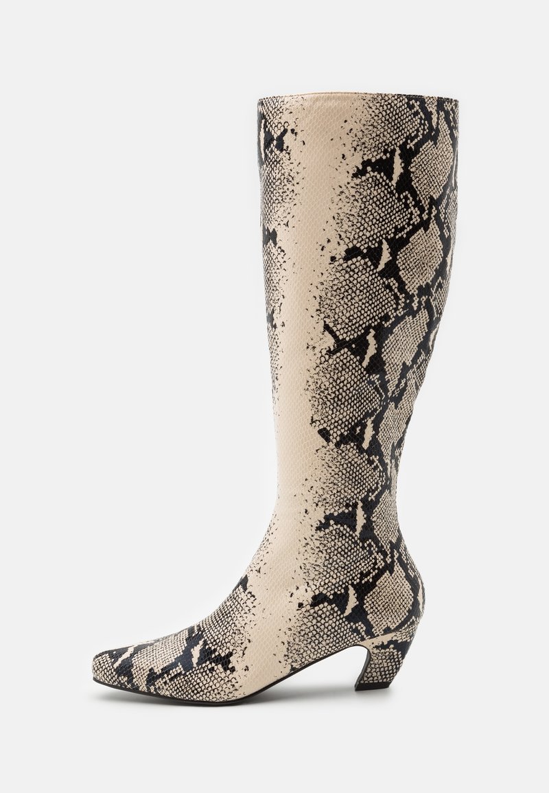 Botte montante jusqu'au genou avec un motif de peau de serpent beige et noire, bout pointu et petit talon incliné, sur fond blanc uni.