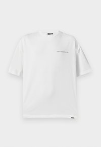 Witte katoenen t-shirt met een relaxed fit, ronde hals en korte mouwen. Voorzien van de zwarte tekst "VERSPIL CULTUUR" aan de voorkant.