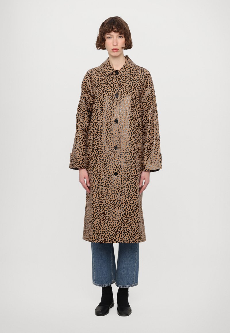 Leopard print raincoat made of glossy material, featuring a collar, long sleeves, and black buttons, paired with wide-leg denim pants.