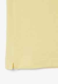 Camicia gialla con colletto, realizzata in un tessuto strutturato, dotata di spacchetti laterali all'orlo inferiore e un design pulito e semplice.