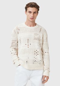 Knit sweater in off-white with textured stitch patterns and intentional distressed detailing. Crew neck and ribbed cuffs complete the design.