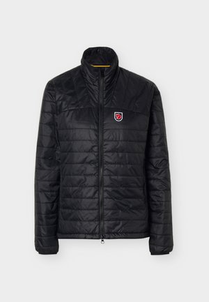 Jachetă neagră matlasată cu guler înalt, fermoar complet frontal și un mic logo roșu și alb în formă de vulpe pe pieptul stâng.