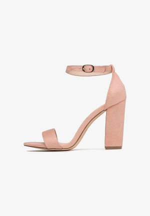 Sandali con tacco in suede rosa pallido, dotati di un'ampia cinghia alla caviglia e una fibbia regolabile, caratterizzati da un'elegante apertura sulla punta e un tacco spesso.