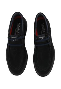 Scarpe slip-on in suede nere Callaghan con lacci elastici blu, punte rotonde e soletta rossa, viste dall'alto su sfondo bianco.