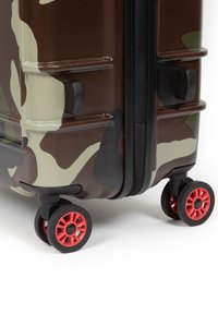 Hårt skal resväska i ett brunt och grönt kamouflage mönster, med en texturerad yta och röda hjul för rörlighet.