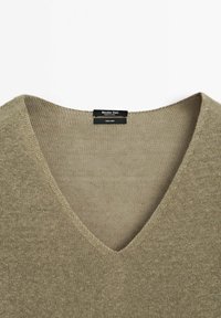 Leinen-V-Ausschnitt-Pullover in hellbeige mit einem weichen, strukturierten Strick. Das Etikett trägt die Aufschrift "Massimo Dutti" und "100% Leinen". Schlichtes Design ohne Verzierungen.