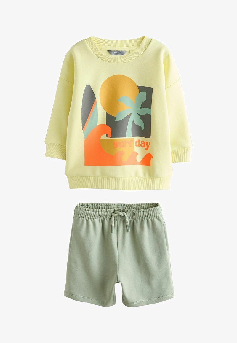 Sudadera amarilla clara con un gráfico temático de surf y mangas largas combinada con pantalones cortos verdes con cintura elástica. Tela suave, diseño casual.