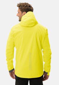 Gelbe wasserdichte Jacke mit Kapuze. Verfügt über reflektierende Details entlang des Rückens und graue Bündchen. Glatte Textur, leichtes Design.