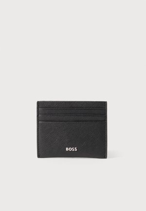 Czarny skórzany etui na karty z czterema kieszeniami na karty i logo "BOSS" w srebrnych literach na środku przodu.