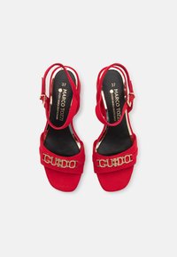 Røde semskede slingback sandaler med en bred rem og en guldfarvet "GUIDO" detalje samt en lille polstret sål.