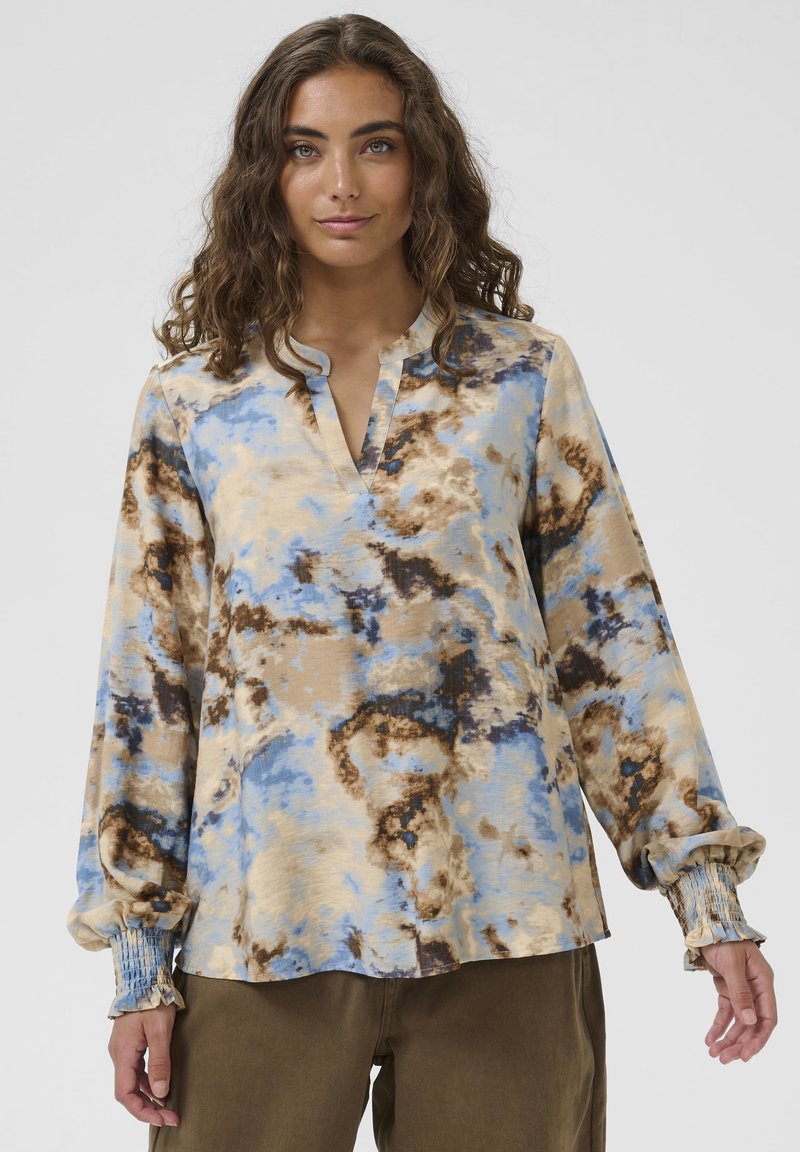 Hosszú ujjú ing könnyű anyagból, kék és barna batikolt mintával, kivágott nyakkivágással és összegyűrt mandzsettákkal. Semleges színalap.