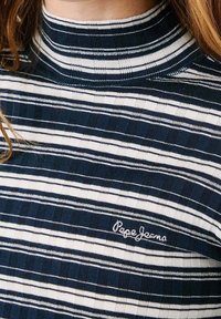 Marinblå och vit randig topp med hög krage, som har en texturerad tyg och broderad "Pepe Jeans" logotyp på vänster sida.