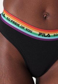 Juodas medvilninis bikini su spalvinga elastinga juosta, puošta vaivorykštės spalvų juostomis ir tekstu "TOKIE DIDŽIUOJAS SU TAVIMI" bei "FILA."